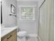 Bathroom with a window, a toilet, and a sink with a wood vanity. Shower stall with patterned curtain at 7674 Chippendale Rd, North Charleston, SC 29420