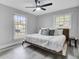 Bright bedroom featuring two windows, modern ceiling fan, and a wooden bed frame with white bedding at 7674 Chippendale Rd, North Charleston, SC 29420