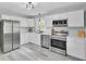 Well-lit kitchen with stainless steel appliances, white cabinets, and modern fixtures. Light-colored wood floor at 7674 Chippendale Rd, North Charleston, SC 29420