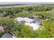 Aerial view showcasing the modern home's white roof amidst green trees near a scenic waterway and distant bridge at 814 Palm Blvd, Isle of Palms, SC 29451