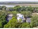 Aerial view of a modern home with a white roof, surrounded by lush trees and other nearby houses at 814 Palm Blvd, Isle of Palms, SC 29451