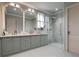 Bright bathroom featuring a double sink vanity with gray cabinetry and a frameless glass shower at 814 Palm Blvd, Isle of Palms, SC 29451