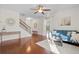 Sun-filled living room featuring hardwood floors, blue sofa, ceiling fan, and stairway to second floor at 9747 Seed St, Ladson, SC 29456