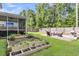 This backyard features a screened-in porch, custom garden beds, a fire pit and a grill, perfect for outdoor enjoyment at 9829 English Elm St, Ladson, SC 29456