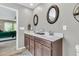 Bathroom featuring a double vanity with dark wood cabinets, dual sinks, oval mirrors and access to the bedroom at 9829 English Elm St, Ladson, SC 29456