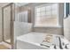 Relaxing bathroom featuring a soaking tub, tiled shower with glass doors, and frosted window at 9829 English Elm St, Ladson, SC 29456