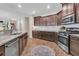 An open concept kitchen showcases stainless steel appliances, dark cabinets, granite counters, and wood-look flooring at 9829 English Elm St, Ladson, SC 29456