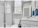 This bathroom features a white sink, toilet, and shower with glass doors, as well as a window at 1017 Marsh Royal St, Summerville, SC 29485