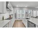 Well-lit kitchen with white cabinets, stainless steel oven, a central island with sink and barstool seating, and backyard access at 1017 Marsh Royal St, Summerville, SC 29485