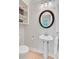 Small half bathroom featuring a pedestal sink, round mirror, and built-in wall shelving at 108 E Walker Dr, Summerville, SC 29483