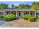 Inviting brick home with a covered entrance, featuring lush landscaping, charming blue shutters, and brick pavers at 108 E Walker Dr, Summerville, SC 29483