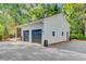 Two-car garage featuring dark gray doors and exterior lighting on a gravel driveway surrounded by woods at 108 E Walker Dr, Summerville, SC 29483