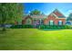 Inviting brick home with manicured lawn, tasteful landscaping, and an American flag on the front porch at 1111 Ole South Ct, Moncks Corner, SC 29461
