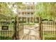 Elegant three-story home with columns and manicured landscaping, viewed through wrought iron fence at 12 Bee St # C, Charleston, SC 29403