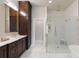 Bright primary bathroom with a glass shower enclosure, and dark stained vanity with storage at 122 Beaufain St # C, Charleston, SC 29401
