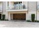 Brick townhome featuring a private garage with a stained-wood door, as well as a small balcony above the garage at 122 Beaufain St # C, Charleston, SC 29401