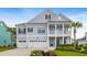 Charming two-story home with a double porch, three-car garage, manicured lawn, and mature palm trees at 1234 Captain Rivers Dr, Charleston, SC 29412
