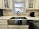 Kitchen with stainless steel farm sink, white cabinets, and tile backsplash at 1329 Camp Rd, Charleston, SC 29412