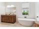 Bright bathroom showcasing a freestanding tub, a wood vanity, and a window overlooking lush greenery at 1474 Blue Cascade Dr, Mount Pleasant, SC 29464