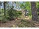 Heavily wooded lot with partial view of dark sided home, and natural landscaping at 205 Woodlawn St, Walterboro, SC 29488