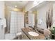 Well-lit bathroom featuring granite countertops, a decorative shower curtain, and neutral-colored tile at 2087 Sterling Marsh Ln, Seabrook Island, SC 29455