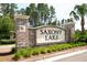 Entrance to Saxony Lake featuring lush greenery and a decorative brick and stucco sign at 283 Saxony Loop, Summerville, SC 29486