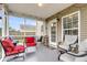 The covered porch features seating options, a ceiling light, and protection from insects, creating a comfortable outdoor space at 301 Edenton Rd, Goose Creek, SC 29445