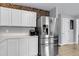 View of the kitchen that features white cabinets, tile floors, stainless steel refrigerator, and brick accent wall at 301 Edenton Rd, Goose Creek, SC 29445