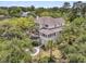 Aerial view of the rear of a two-story home surrounded by mature trees with a landscaped yard and deck at 4702 Blockhouse Ln, Hollywood, SC 29449