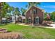 All brick home with tidy lawn and mature landscaping, including palm trees with American flag in yard at 569 Pointe Of Oaks Rd, Summerville, SC 29485