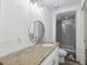 Bright bathroom featuring a granite countertop, round mirror, and a glass-enclosed walk-in shower at 634 Rutledge Ave, Charleston, SC 29403