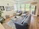 Bright living room featuring a blue sofa, armchairs, and natural light from the windows overlooking the backyard at 689 W Butternut Rd, Summerville, SC 29483