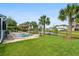 Backyard with a lush green lawn, in-ground pool, black aluminum fence, mature palm trees and lake views at 6910 Tanner Hall Blvd, Hanahan, SC 29410