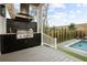 Outdoor kitchen featuring modern grill, sink, cabinets, and view of backyard pool at 71 Moultrie St, Charleston, SC 29403