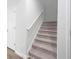 Carpeted staircase featuring neutral walls, white trim, and a secure handrail for safe navigation at 740 Meadowbrook Lane, Summerville, SC 29486