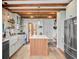 Farmhouse kitchen with white cabinets, stainless appliances, wood island, and wooden ceiling beams at 11 Francis St, Charleston, SC 29403