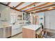 Farmhouse kitchen boasts white cabinets, stainless appliances, a center island, and wooden ceiling beams at 11 Francis St, Charleston, SC 29403
