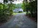 Single Gathering home in a wooded area, featuring well-maintained landscaping and a long, gravel driveway at 1671 Dawson Branch Rd, Summerville, SC 29483