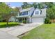 Attractive two-story home featuring a well-kept lawn, mature tree, covered front porch, and attached garage at 1703 Dotterers Run, Charleston, SC 29414