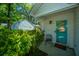 Inviting front entrance with a vibrant turquoise door, lush greenery, and a cozy sitting area at 2016 Wild Flower Ln, Charleston, SC 29414