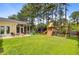 Spacious backyard with a patio, screened porch, playset, and mature trees, ideal for outdoor enjoyment at 230 Sweet Alyssum Dr, Ladson, SC 29456