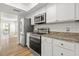 Modern kitchen with stainless steel appliances, white cabinets, granite countertops, and hardwood floors at 2333 Tall Sail Dr # G 607, Charleston, SC 29414