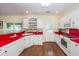 Well-lit kitchen showcasing white cabinets, red countertops, and hardwood flooring at 2613 Rivertowne Pkwy, Mount Pleasant, SC 29466