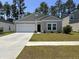 Charming single-story home featuring a well-manicured lawn, attached garage, and inviting front entrance at 305 Camellia Bloom Dr, Moncks Corner, SC 29461