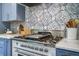 Chef's kitchen with custom cabinets, stainless steel stove, marble countertops, and designer backsplash at 408 N Palmetto St, Summerville, SC 29483