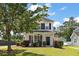 Two-story house with inviting front porch, lush lawn, mature tree, and private driveway at 8987 Planters Row Ln, Summerville, SC 29485
