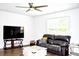Bright living room featuring a dark leather sofa, sleek ceiling fan, and hardwood floors at 9694 Roseberry St, Ladson, SC 29456