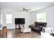 Bright living room featuring a dark leather sofa, sleek ceiling fan, and hardwood floors at 9694 Roseberry St, Ladson, SC 29456