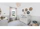 Bright bedroom features a white crib, modern light fixture, window with curtains, and unique decorations at 1009 Swamp Rose Run, Summerville, SC 29485