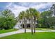 Charming raised beach house with white stairs and palm trees in the front yard at 1064 Blackbear Dr, Edisto Island, SC 29438